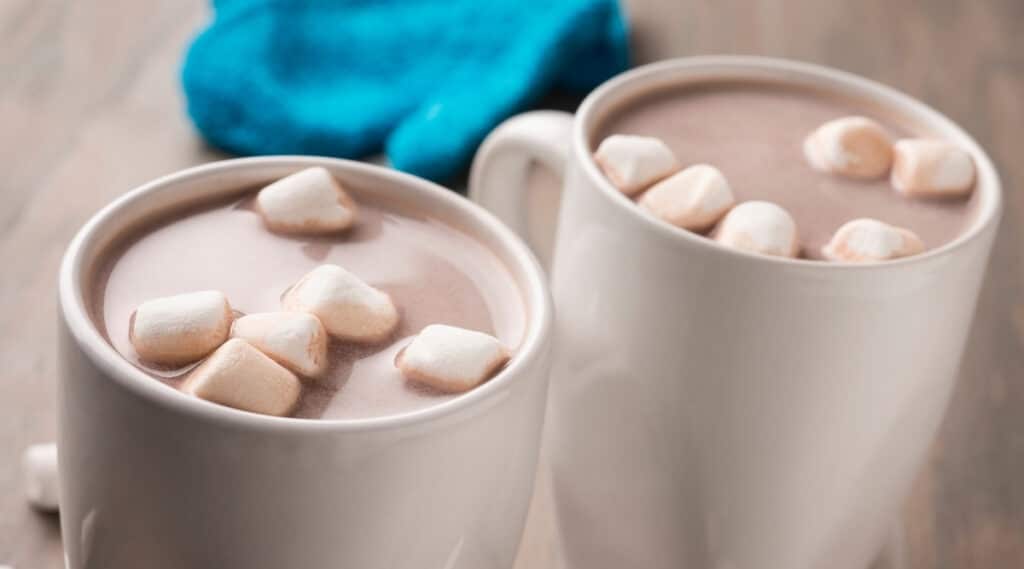 A cup of hot chocolate next to a cup of hot cocoa. 